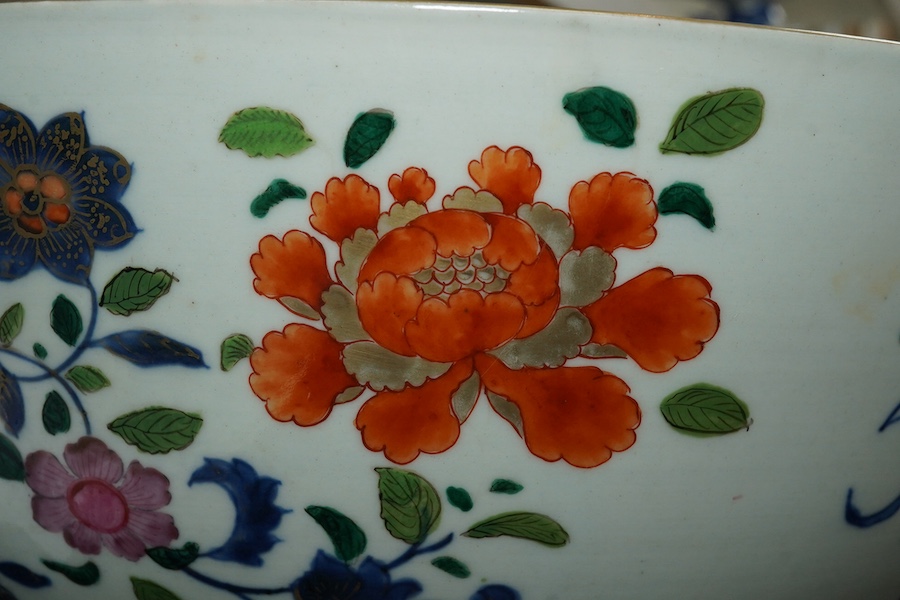 A large Chinese famille rose punch bowl, Qianlong period, the exterior painted with flowers in a fenced garden, the interior with a flower bouquet within a garland of flowers, 40.5cm diameter, wood stand. Condition - som